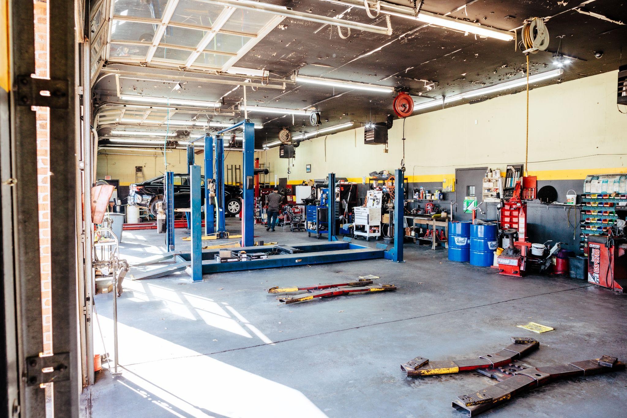 An interior view of an automotive repair shop with vehicle lifts and tools