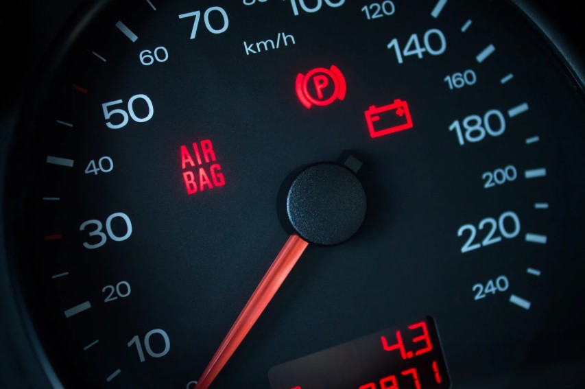 Car dashboard showing red warning lights including parking brake, battery, and airbag indicators