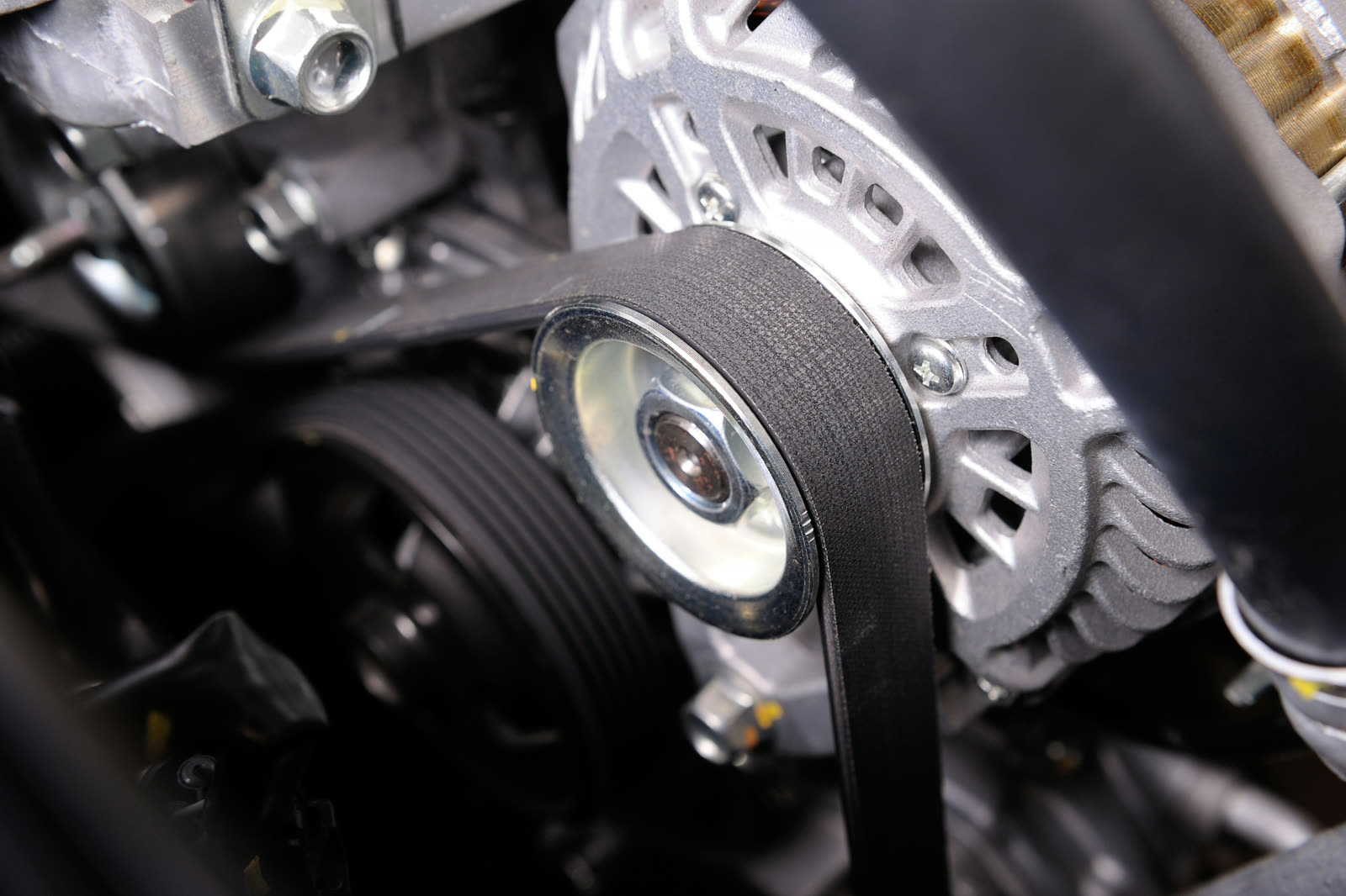 Technician inspecting engine belts and hoses for cracks