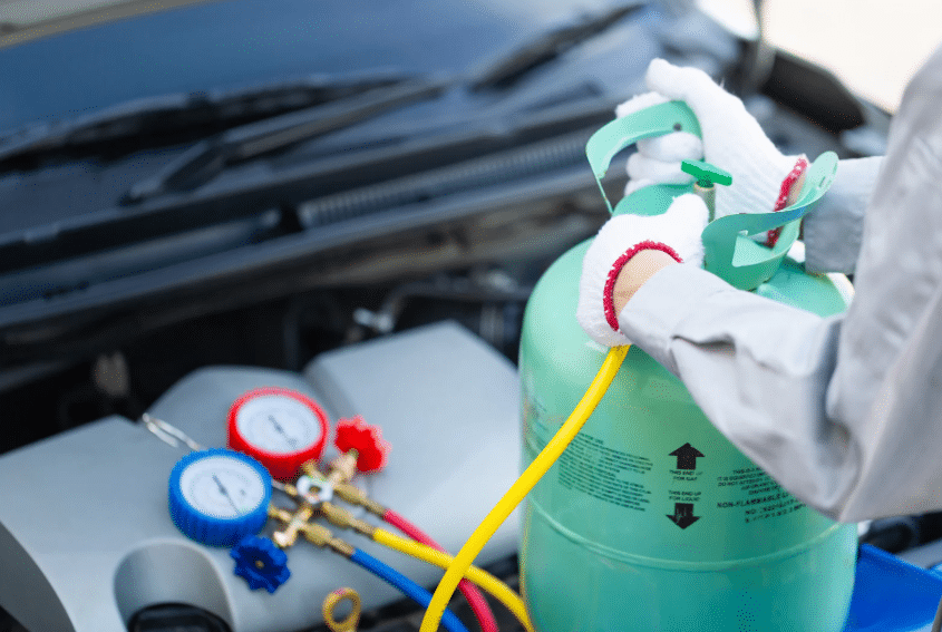 Technician refilling refrigerant in a car AC system, showing the process behind how often do you have to recharge your ac in your car.