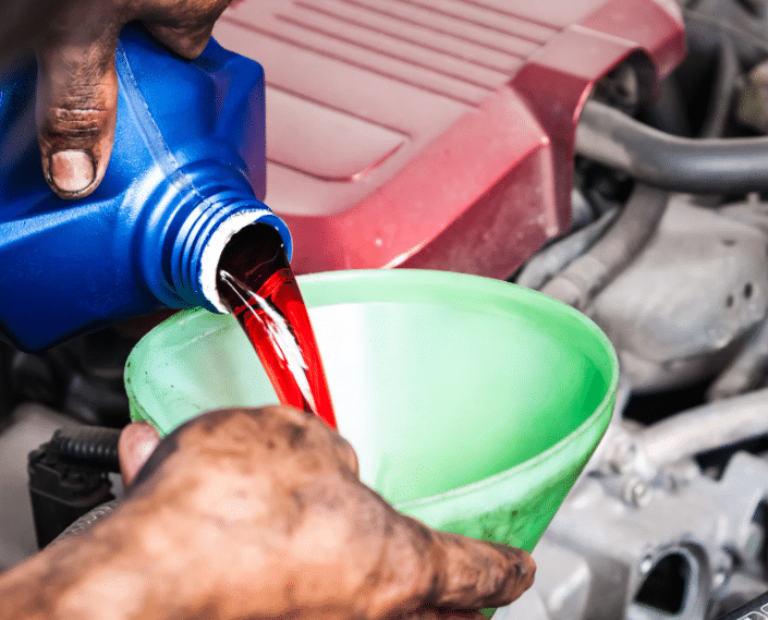 Blue Ridge Automotive | How Transmission Maintenance Keeps Your Vehicle Running Longer Dirty hands pouring fresh transmission fluid into a car during a transmission maintenance service.