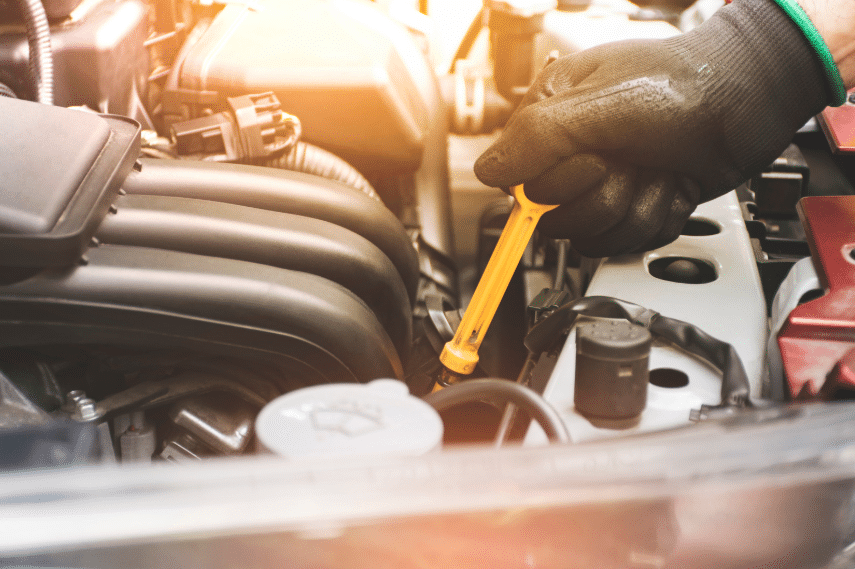 Blue Ridge Automotive | How Transmission Maintenance Keeps Your Vehicle Running Longer Auto technician checking fluid levels with a dipstick as part of routine transmission maintenance.