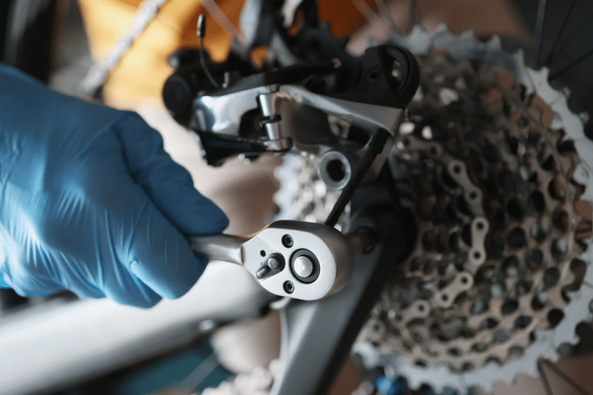 Mechanic using a wrench on a gear system, highlighting mechanical roots in the history of auto mechanics.