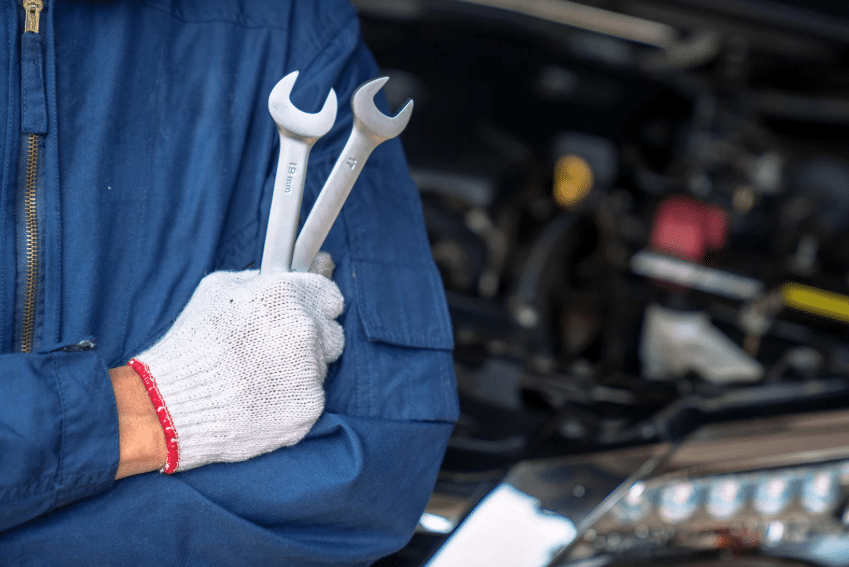 Close-up of mechanic with wrenches, symbolizing hands-on skills throughout the history of auto mechanics.
